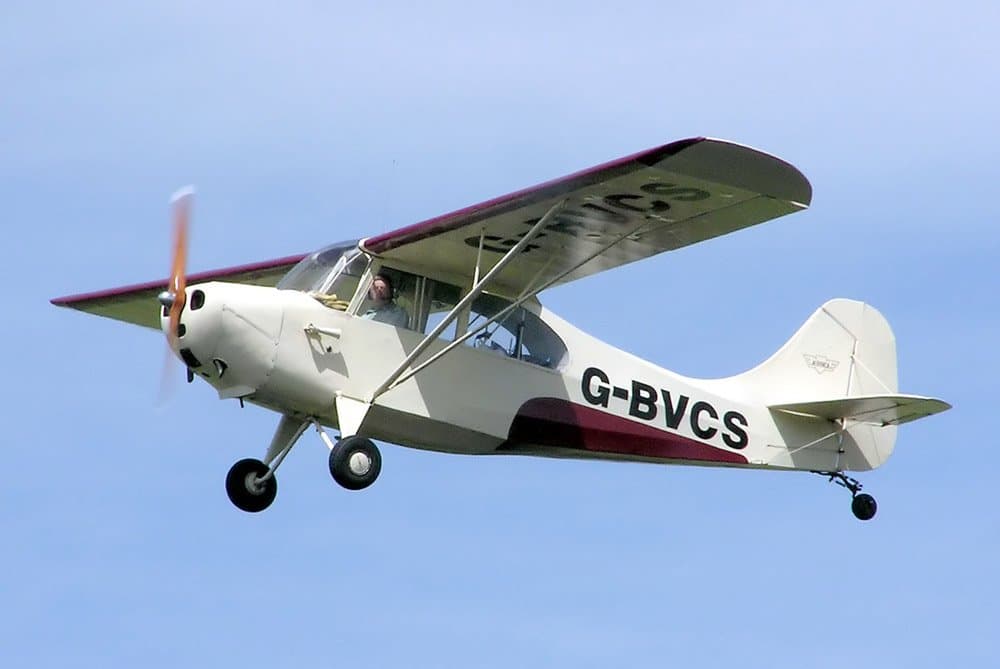 Un Aeronca 7AC Champion jaune stationné sur l'herbe, vu de trois quarts avant