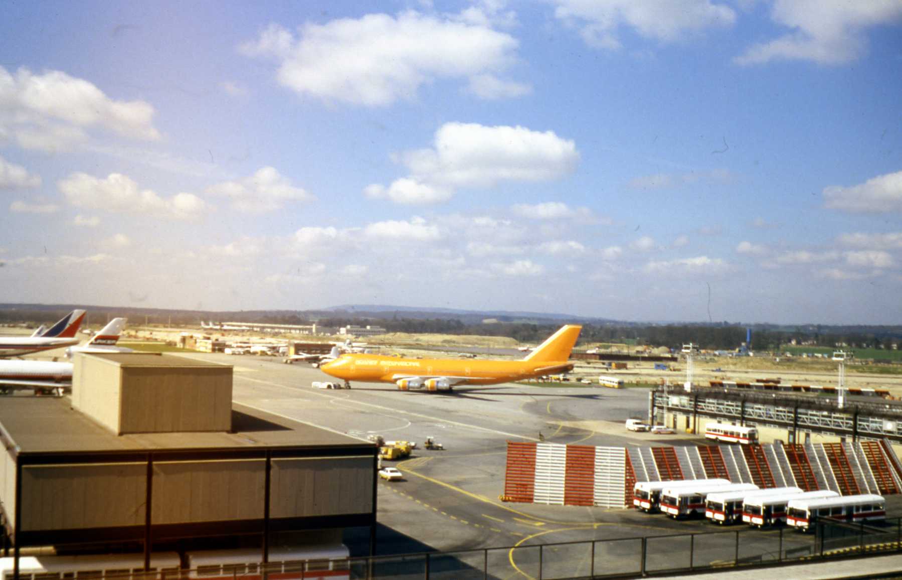 Un Boeing 747-200 cargo à la livrée orange roulant devant une aérogare, à la fin des années 1970 ou au début des années 1980