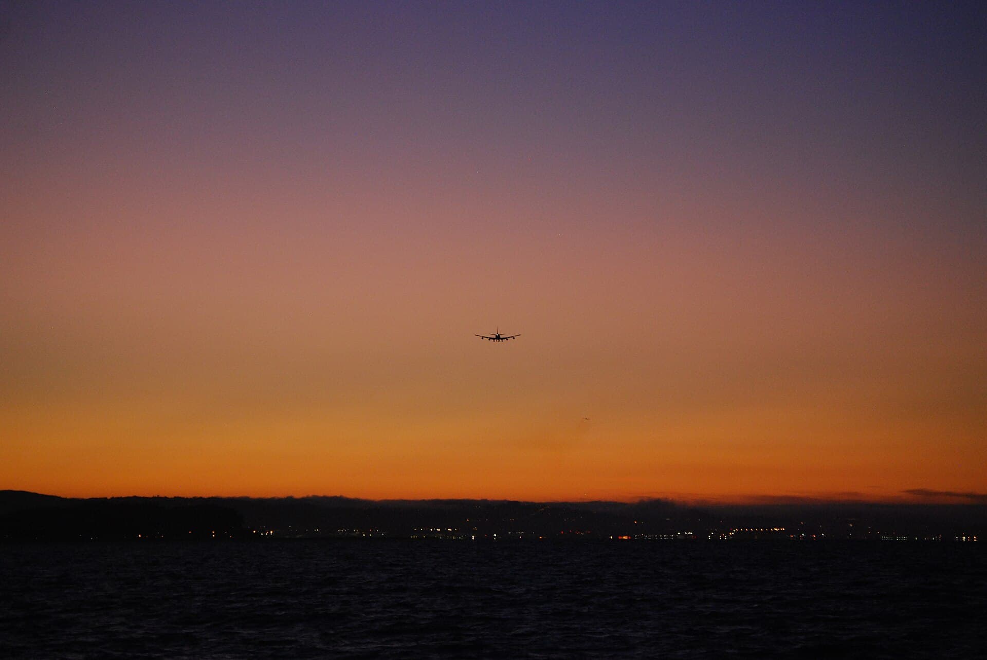 Un Boeing 747-400 en virage dans la lumière chaude du soir, ses extrémités d'ailes effilées et son winglet accrochant le soleil