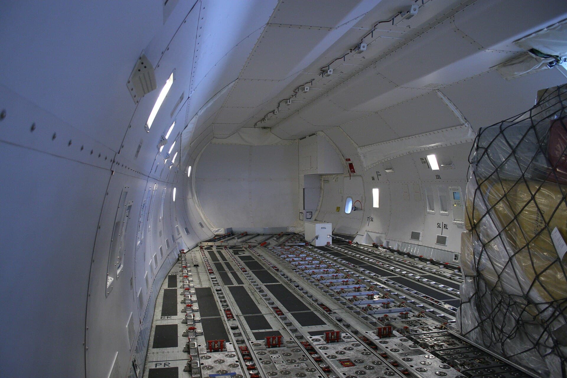La soute principale vide d'un Boeing 747-8F, ses rouleaux de plancher motorisés et ses rails de guidage latéraux s'étirant vers le nez