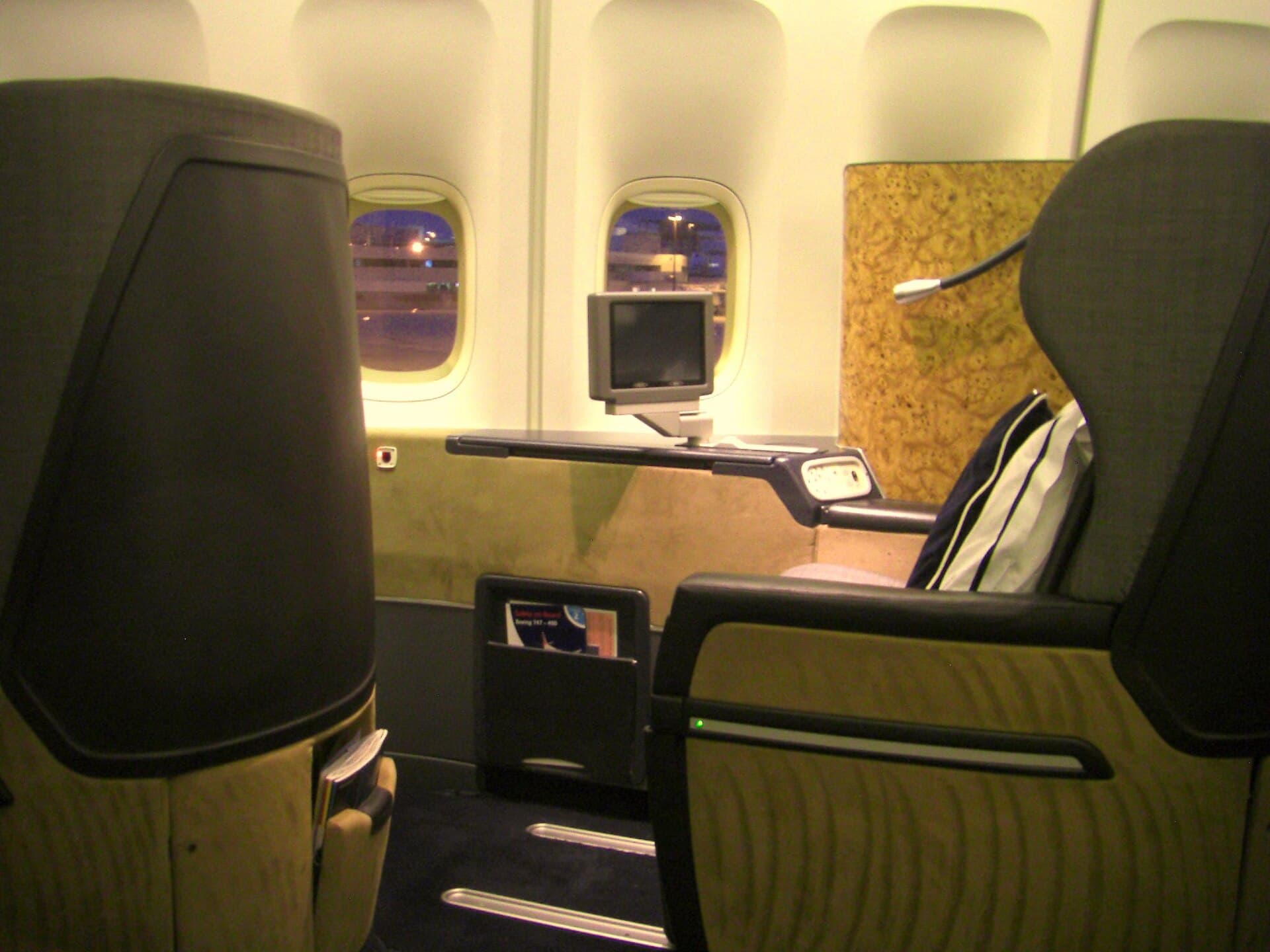 Une cabine First de British Airways à bord d'un 747, de larges sièges en cuir bien espacés sous des liseuses tamisées