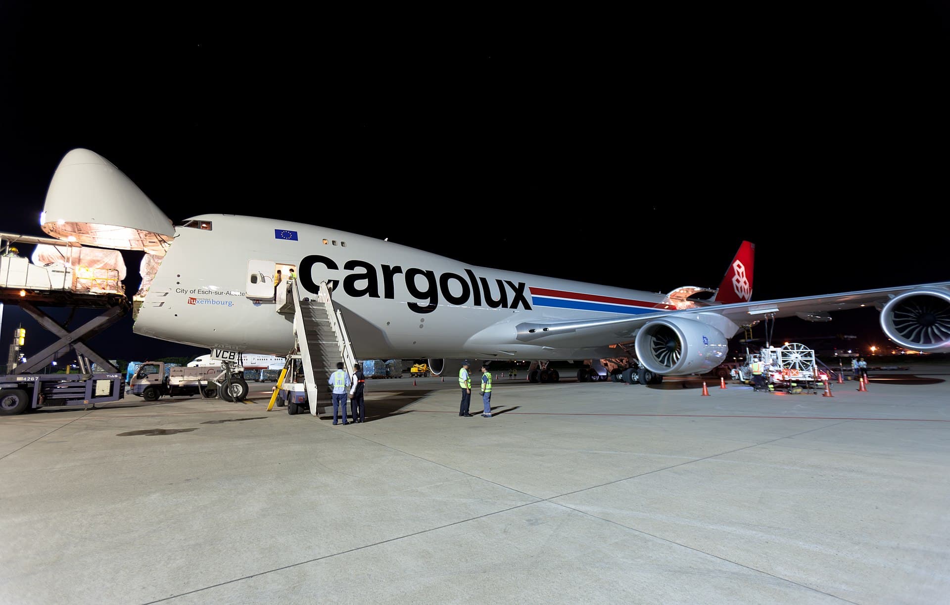 Un Boeing 747-8F de Cargolux sur le tarmac de nuit, son nez articulé relevé pour le chargement du fret