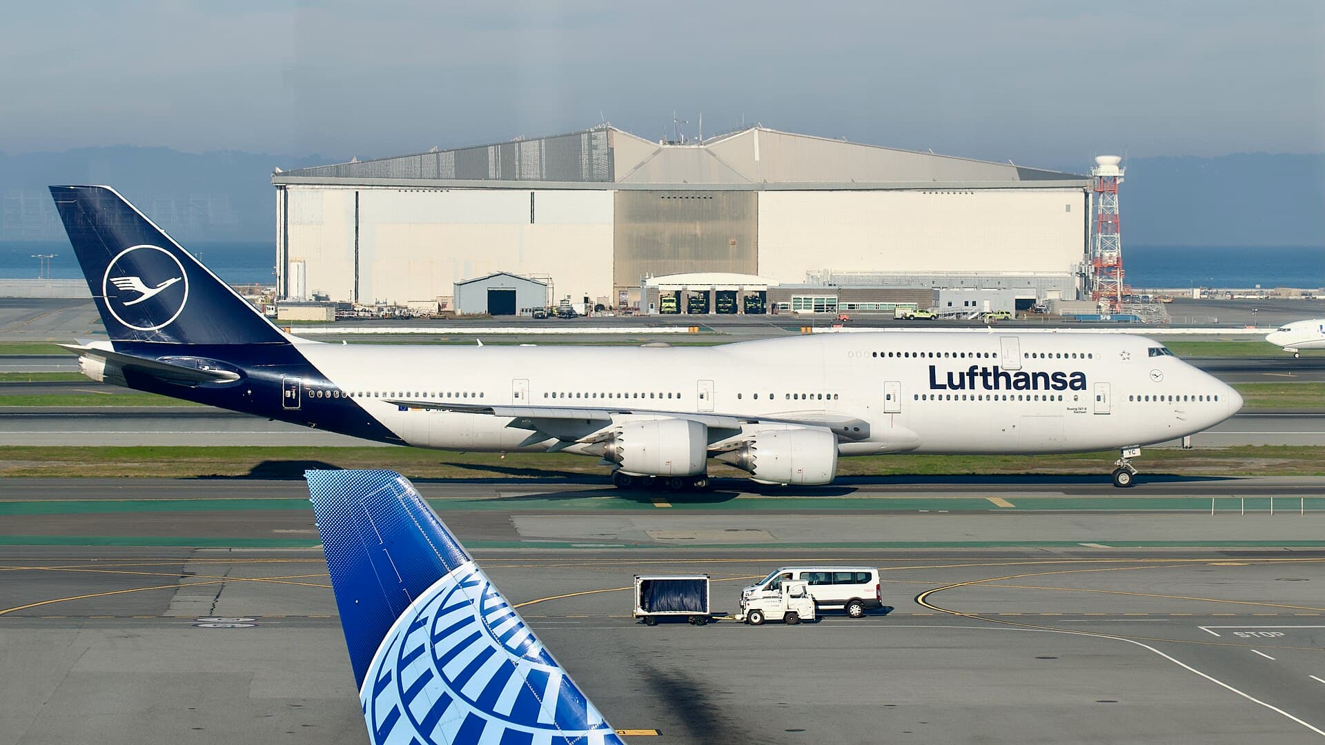 Un Boeing 747-8 de Lufthansa roulant au départ de San Francisco, son pont supérieur allongé et ses extrémités d'ailes effilées visibles de profil