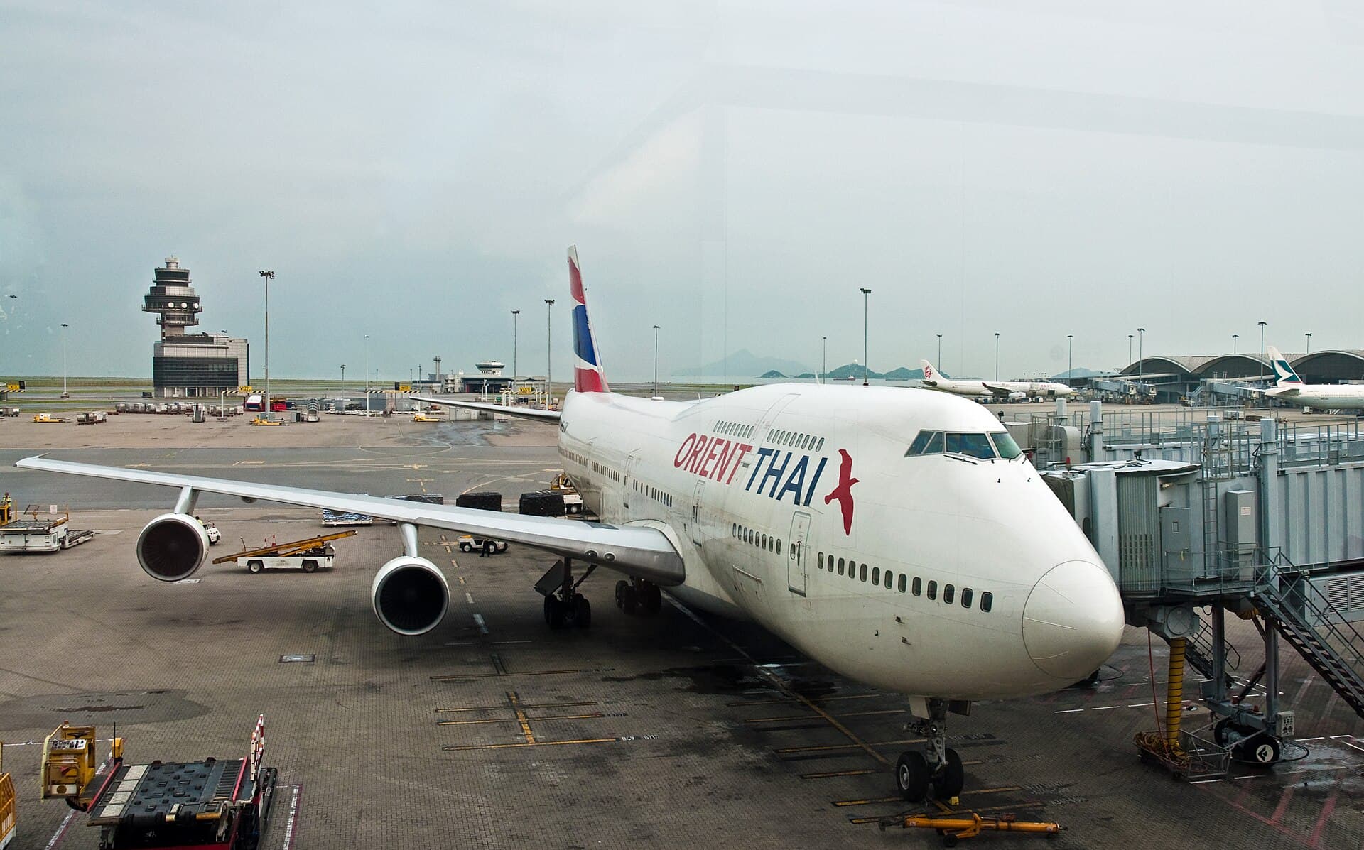Un Boeing 747-300 d'Orient Thai stationné à une passerelle de l'aéroport international de Hong Kong, son pont supérieur allongé visible sur le dos du fuselage