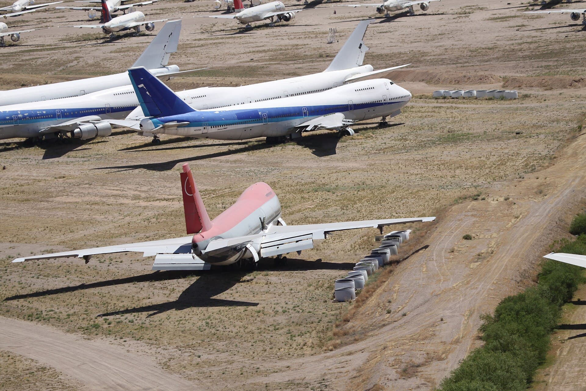 Des Boeing 747 retirés du service stationnés en rangs dans un site de stockage désertique, moteurs bâchés et peinture ternie par le soleil
