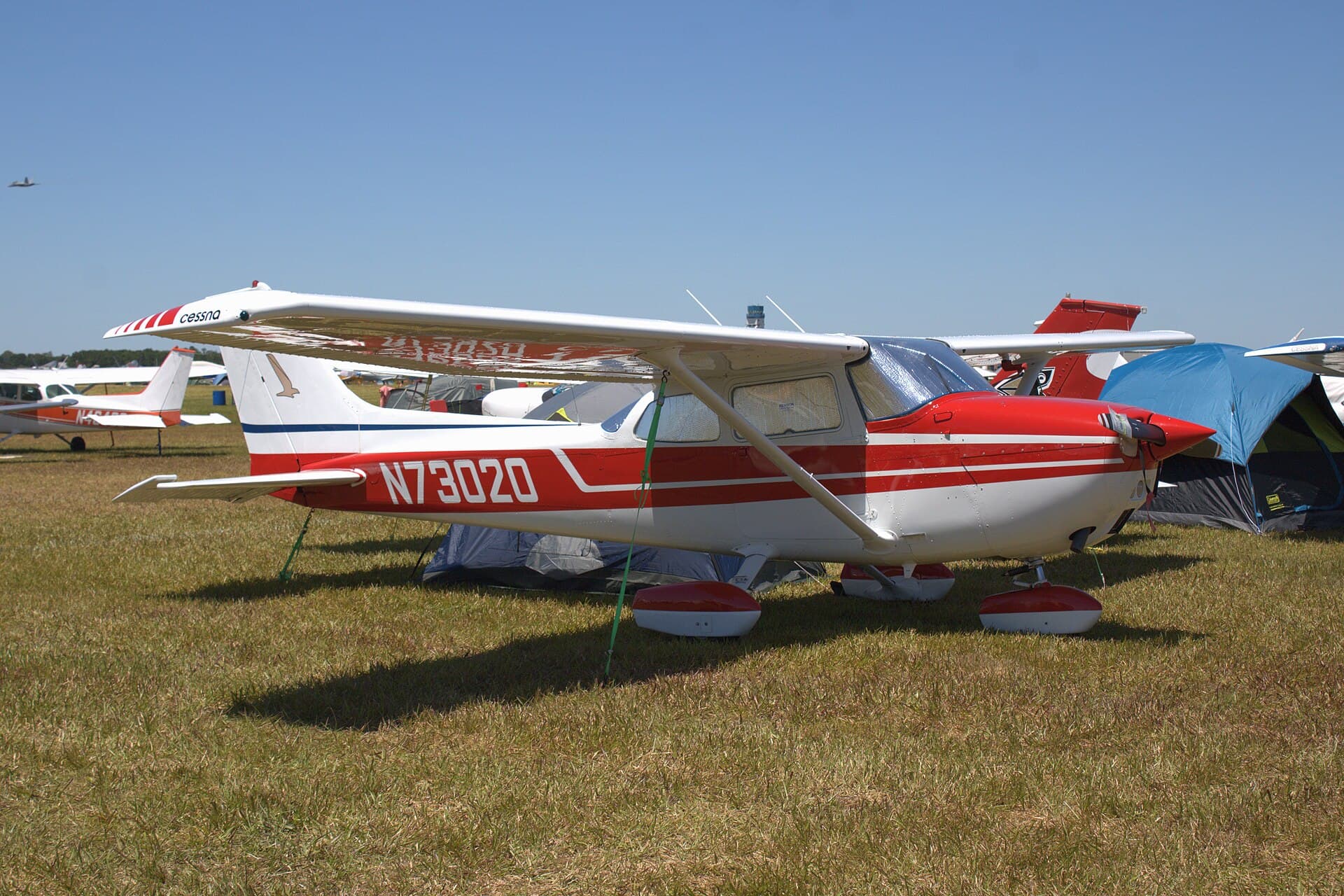 A red-and-white 1970s Cessna 172M Skyhawk parked at a fly-in