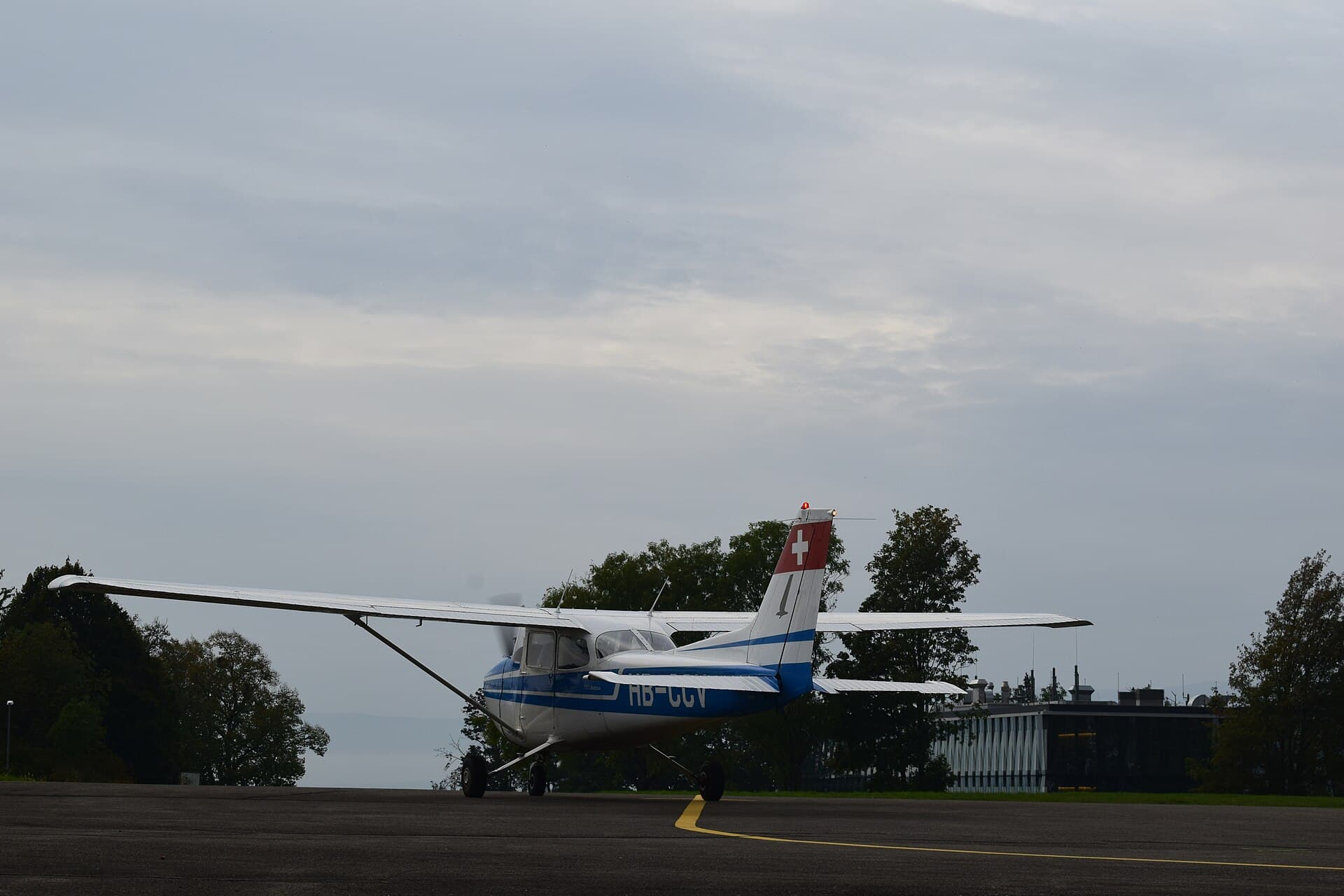 A Swiss-registered Cessna 172 holding at the runway edge under an overcast sky