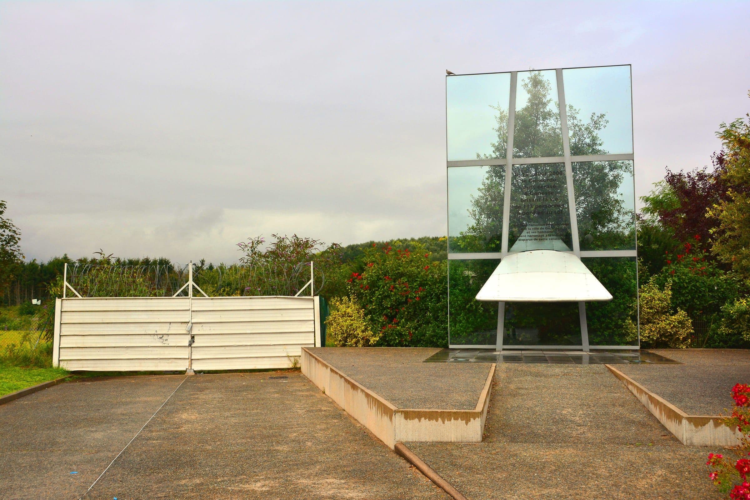 The memorial at Gonesse to the one hundred and thirteen people killed in the crash of Air France flight 4590 on 25 July 2000, with the crash site behind the gates