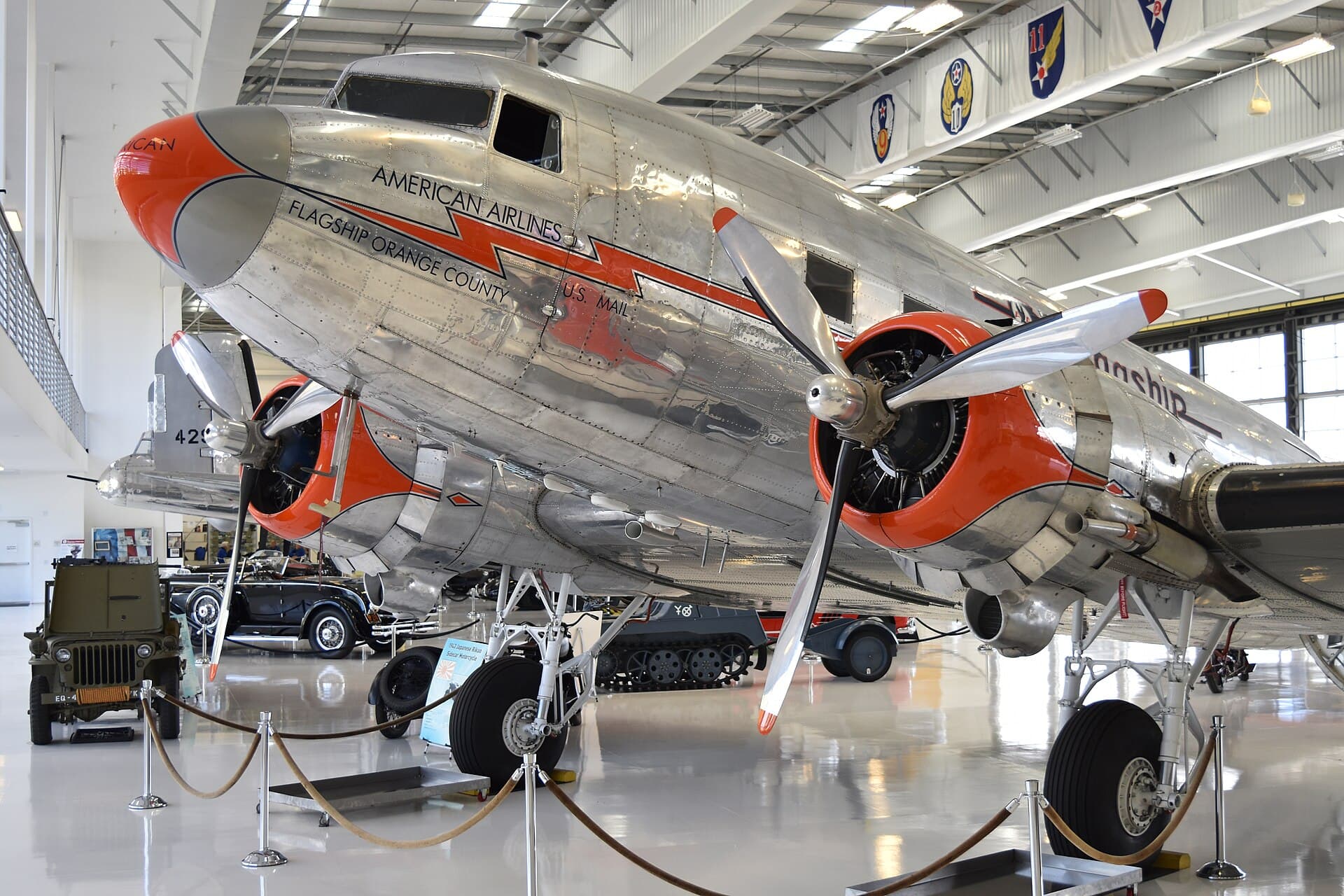 Un Douglas DC-3/C-47 restauré, construit en 1944 et aujourd'hui peint aux couleurs 'Flagship' d'American Airlines, exposé dans un musée aux côtés de véhicules d'époque