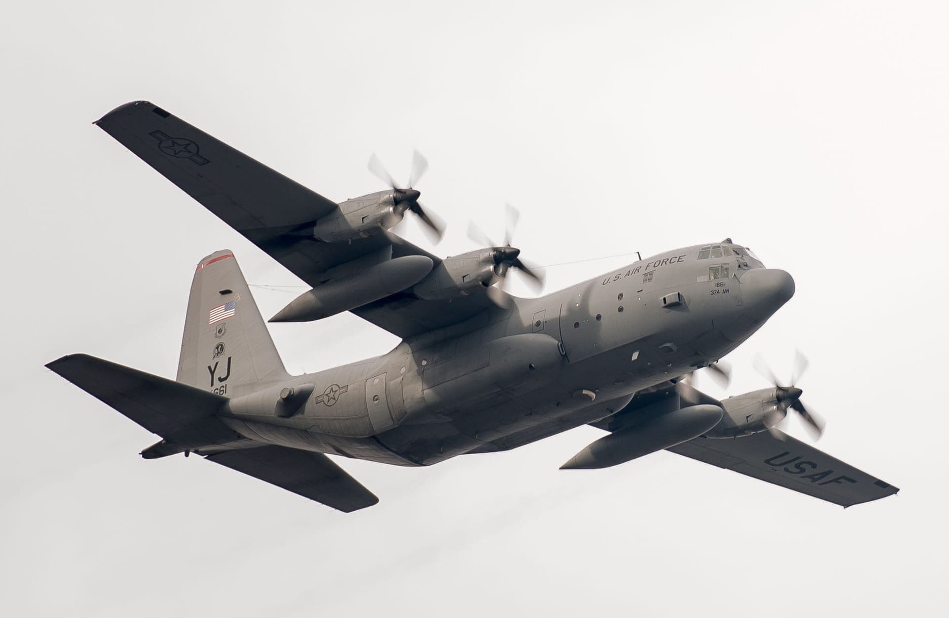 Un C-130 Hercules de l'US Air Force du 36th Airlift Squadron en virage au-dessus de la base aérienne de Yokota, au Japon, vu de trois quarts avant : aile haute, quatre turbopropulseurs et empennage relevé nettement visibles