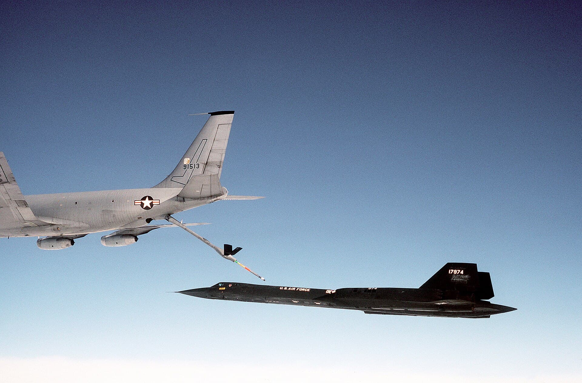 A KC-135Q tanker refuelling an SR-71 in flight, boom connected, both aircraft against a clear blue sky