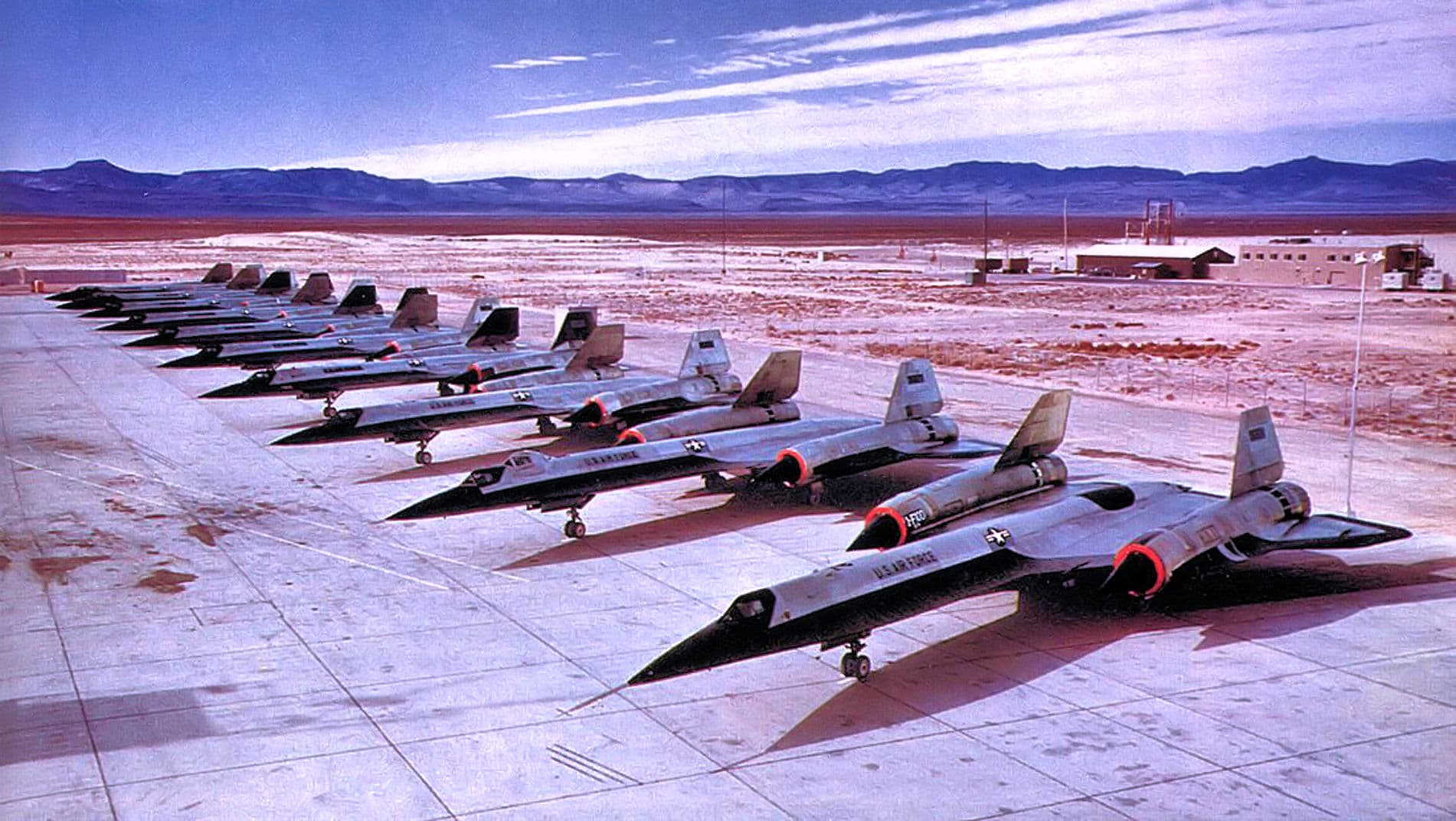 Ten Lockheed A-12 aircraft lined up diagonally on the ramp at Palmdale's Plant 42, their single cockpits and unpainted titanium-and-black finish visible