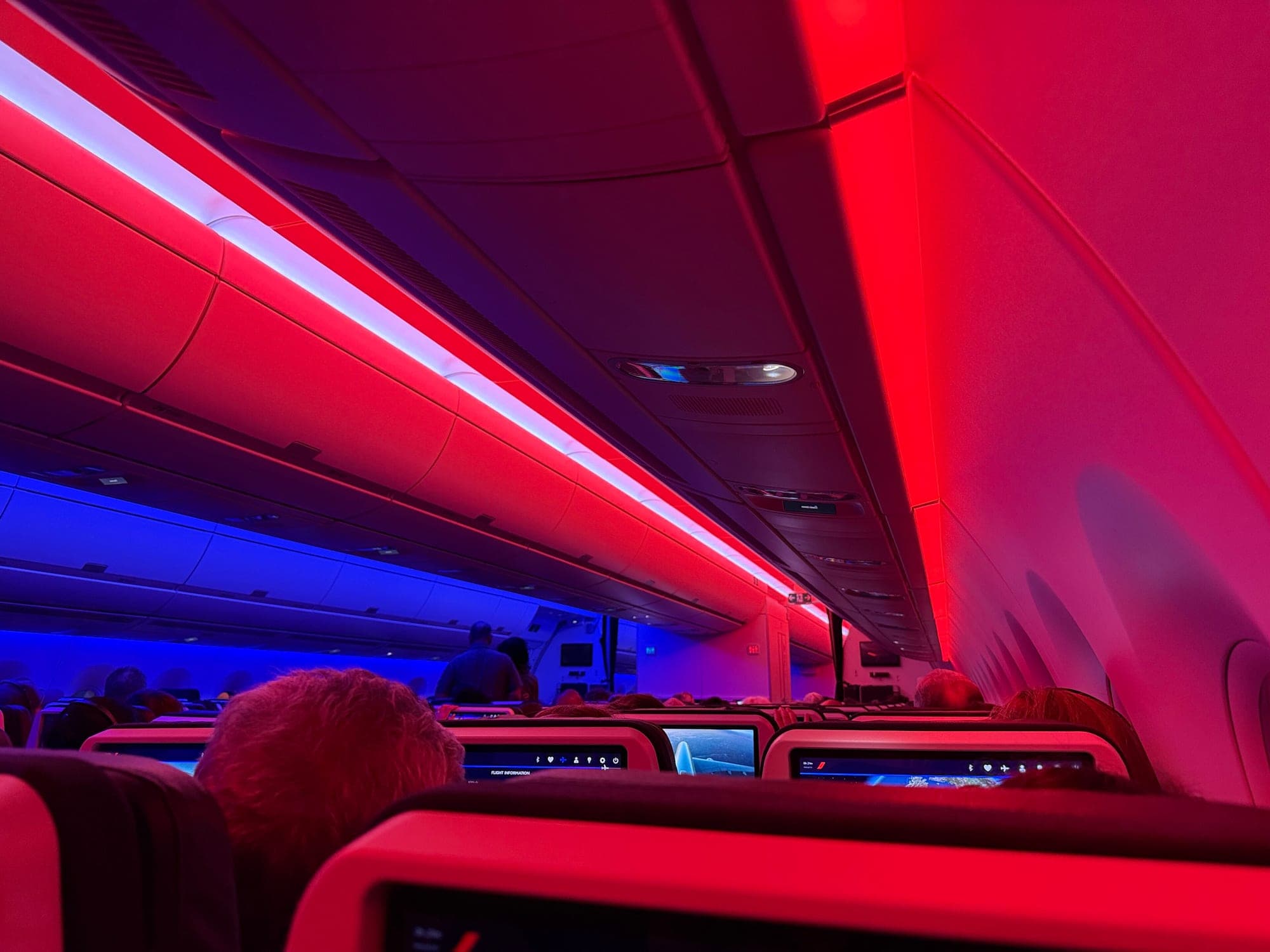 The economy cabin of an Air France Airbus A350-900 under blue, white and red mood lighting.