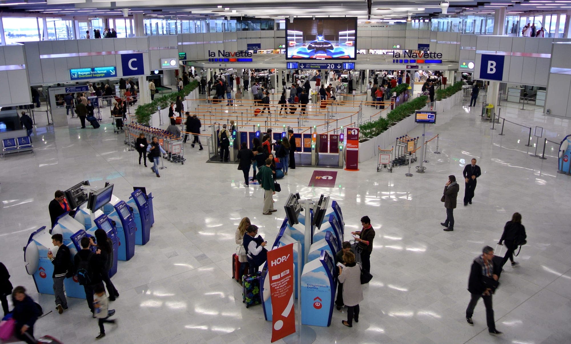 The Air France Navette shuttle hall at Orly Ouest, with self-service check-in kiosks and Air France and HOP! signage.