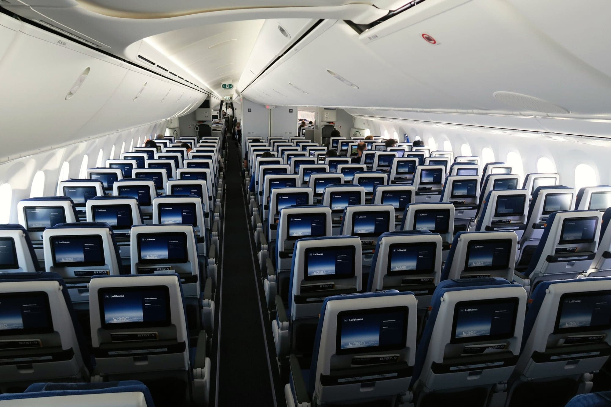 The economy cabin of a Lufthansa Boeing 787-9 seen from the rear in October 2022: nine seats abreast, a screen in every seat back.