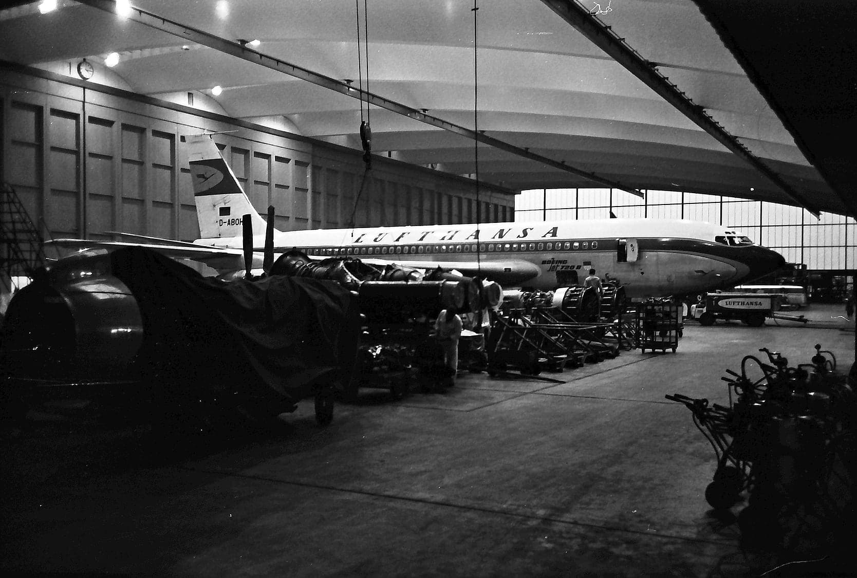 Inside the Lufthansa maintenance hangar at Frankfurt on 27 November 1962, an airliner in the hall behind rows of workshop equipment.