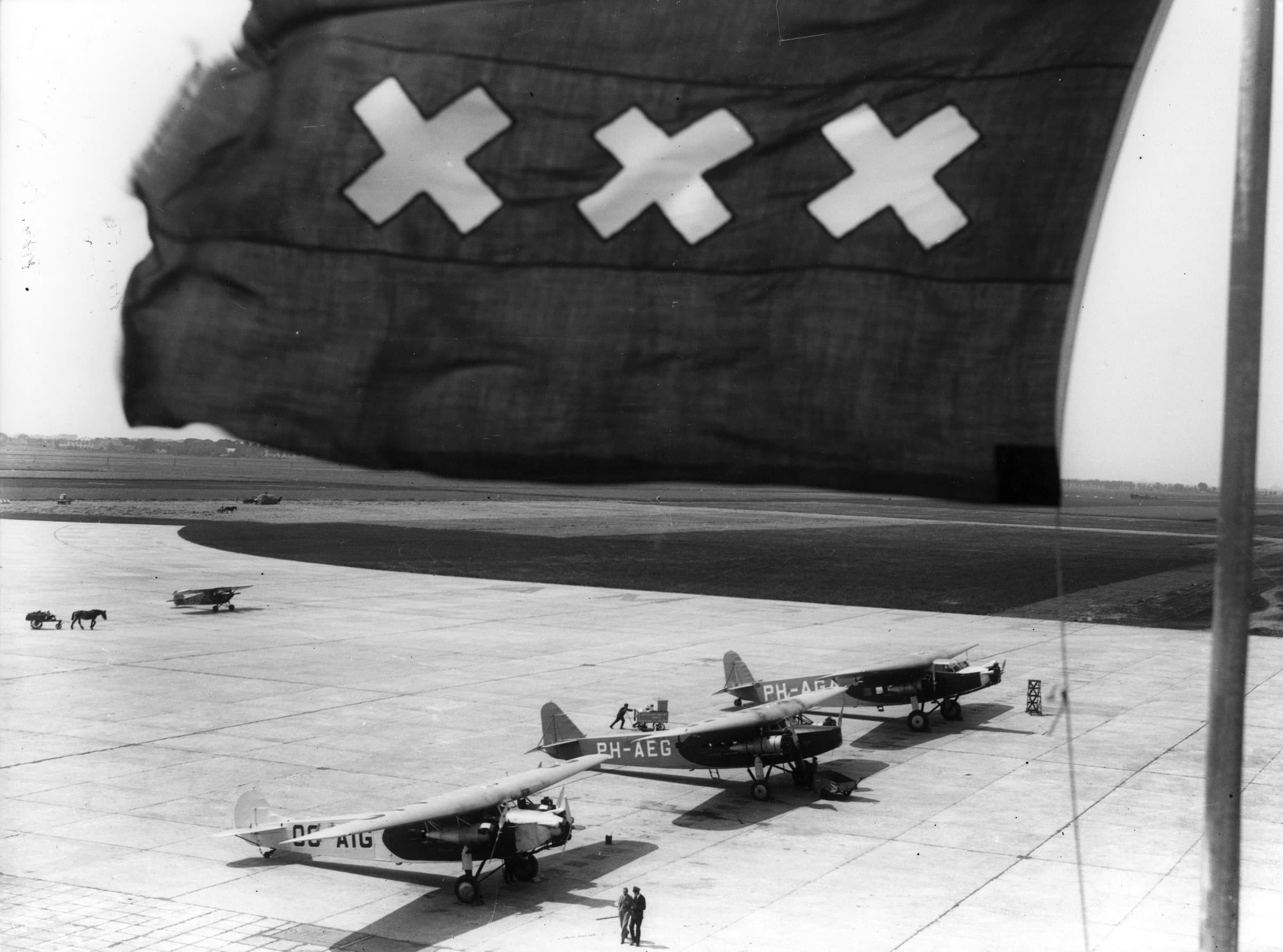 The flag of Amsterdam flying over the apron in the 1920s, with airliners parked beyond