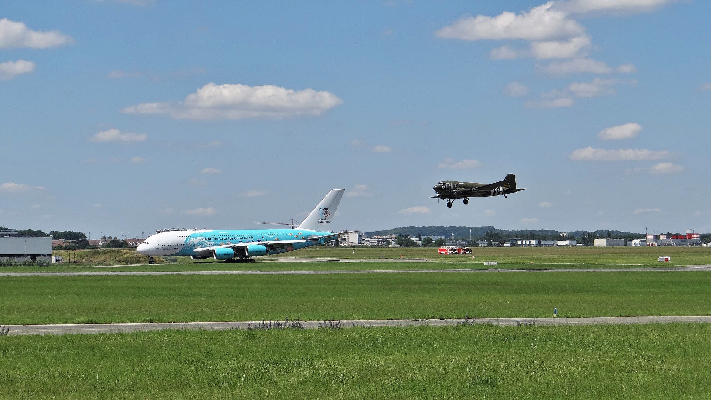 A vintage twin-engine piston airliner landing at Le Bourget during the 2019 Paris Air Show while an Airbus A380 taxis behind