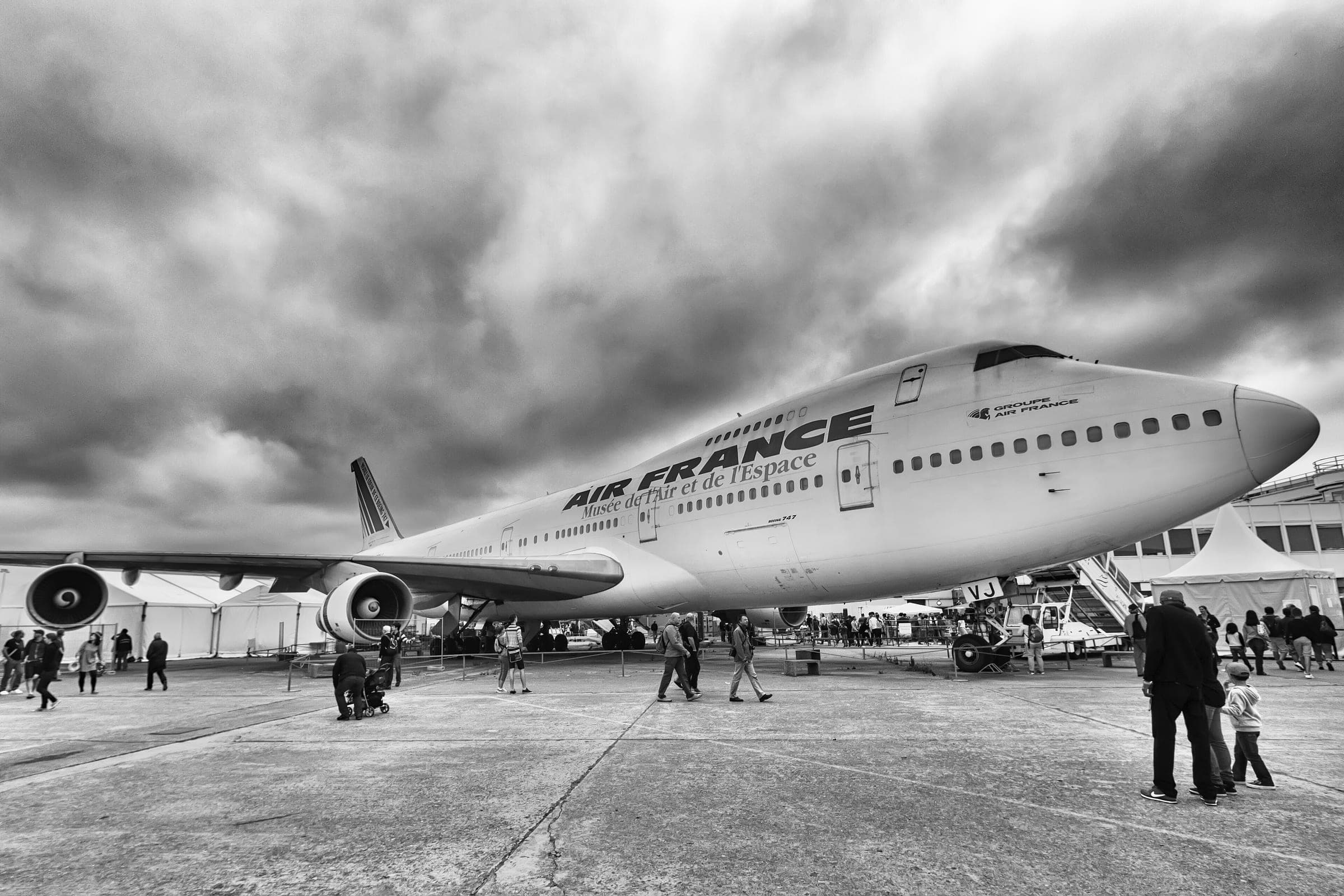 The museum's Air France Boeing 747-128 on the Le Bourget apron under a heavy sky, visitors walking beneath its wing