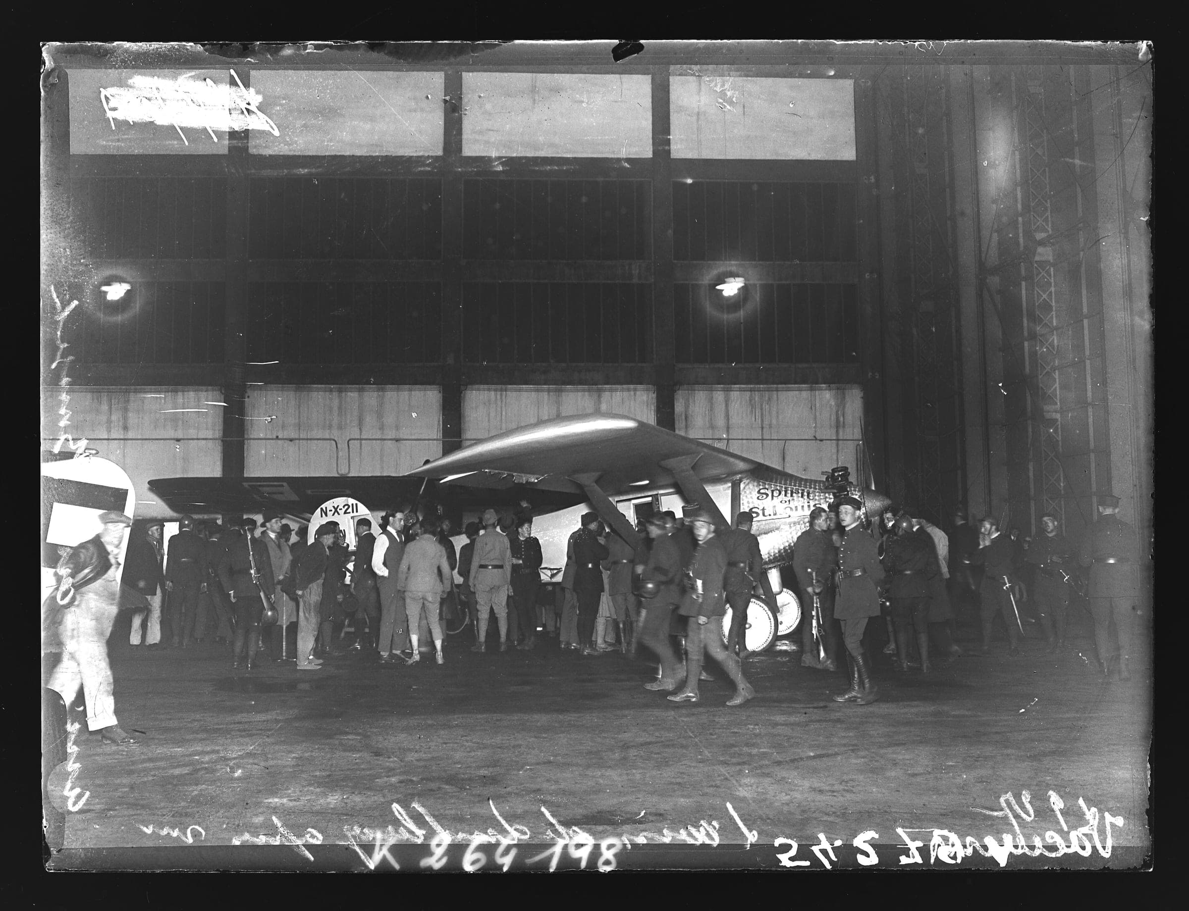 Lindbergh's Spirit of St. Louis inside a hangar at Le Bourget after its arrival, surrounded by onlookers
