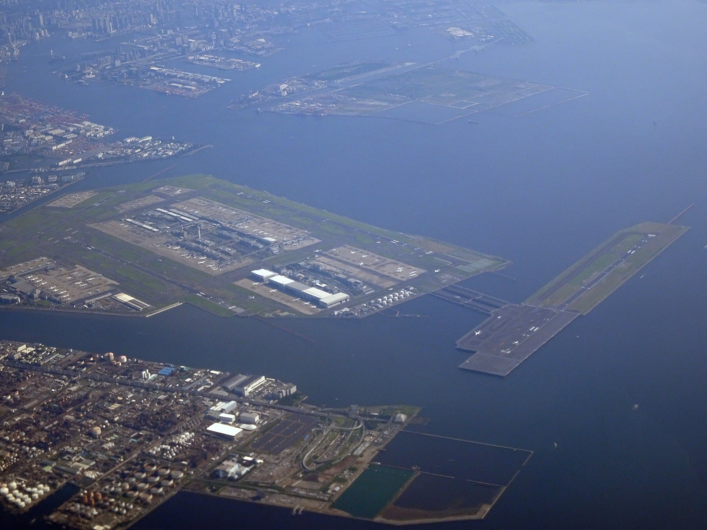 Haneda from the air in 2024: the airport on reclaimed land in Tokyo Bay, with Runway D standing out in the water on its island
