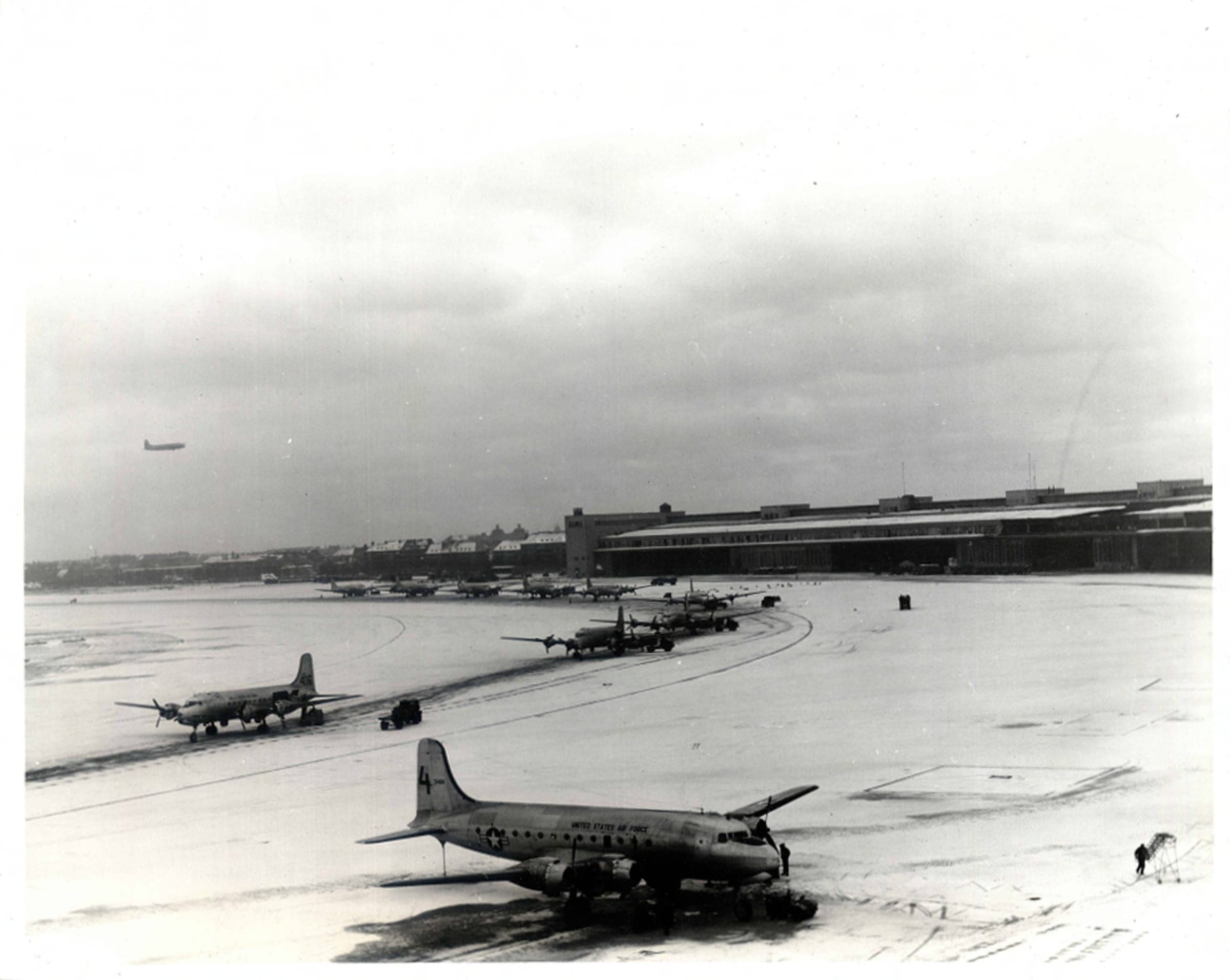 Des C-54 déchargeant sur l'aire semi-circulaire enneigée de Tempelhof