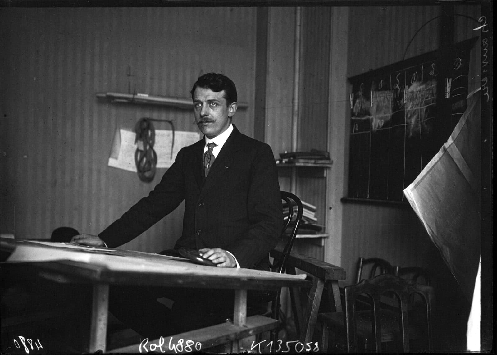Lucien Chauvière, fabricant de l'hélice Intégrale, assis à une table à dessin dans son atelier.