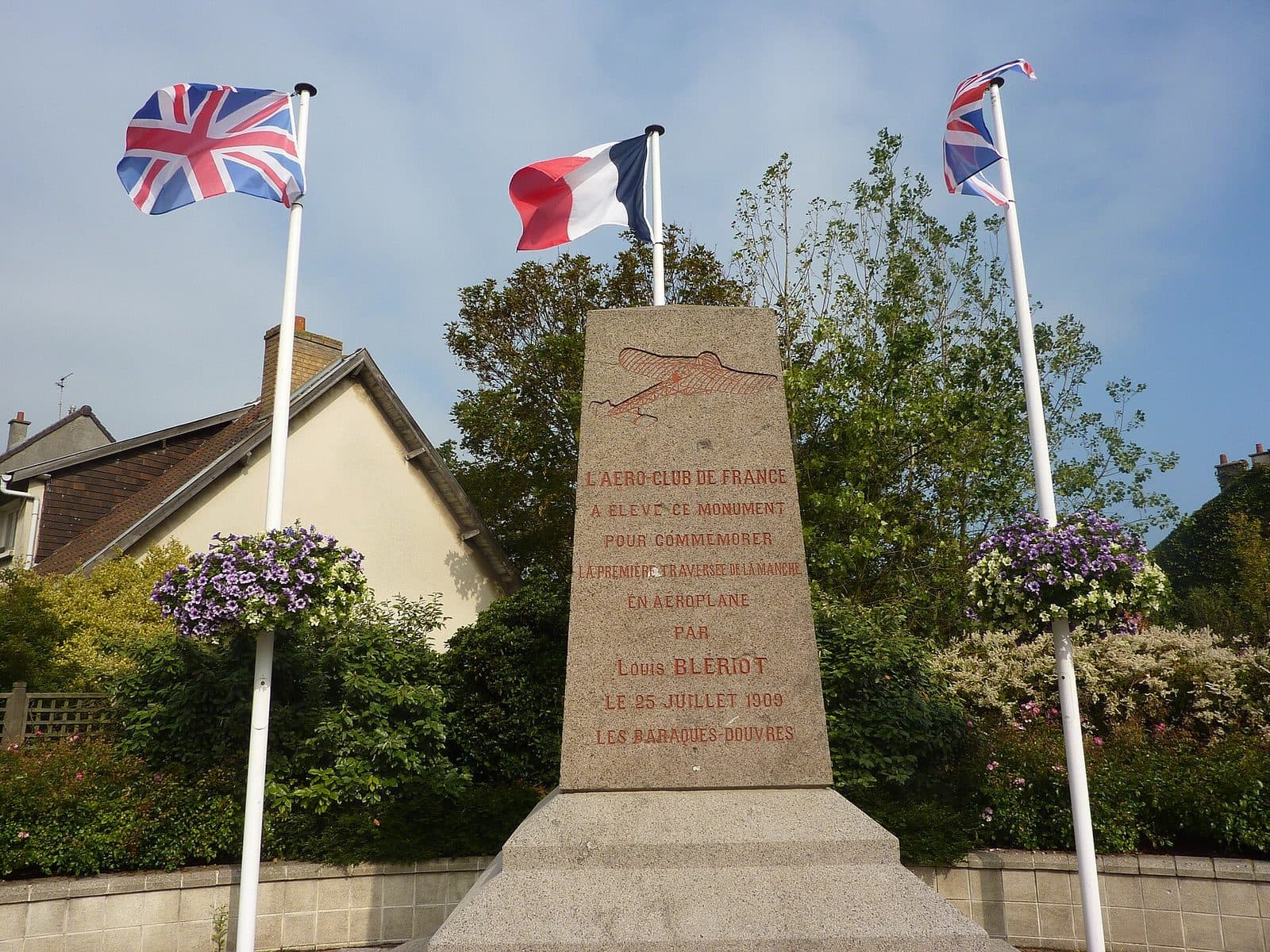 Le monument de pierre à Louis Blériot à Sangatte-Blériot-Plage, encadré des drapeaux britannique et français.