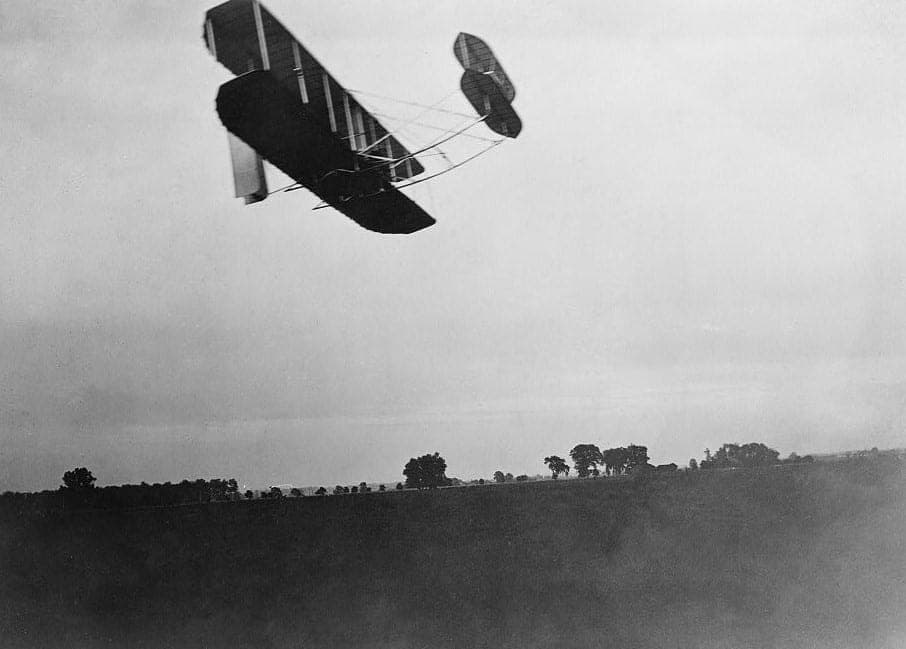 Le Wright Flyer III de 1905 en vol au-dessus de Huffman Prairie, vu de profil.