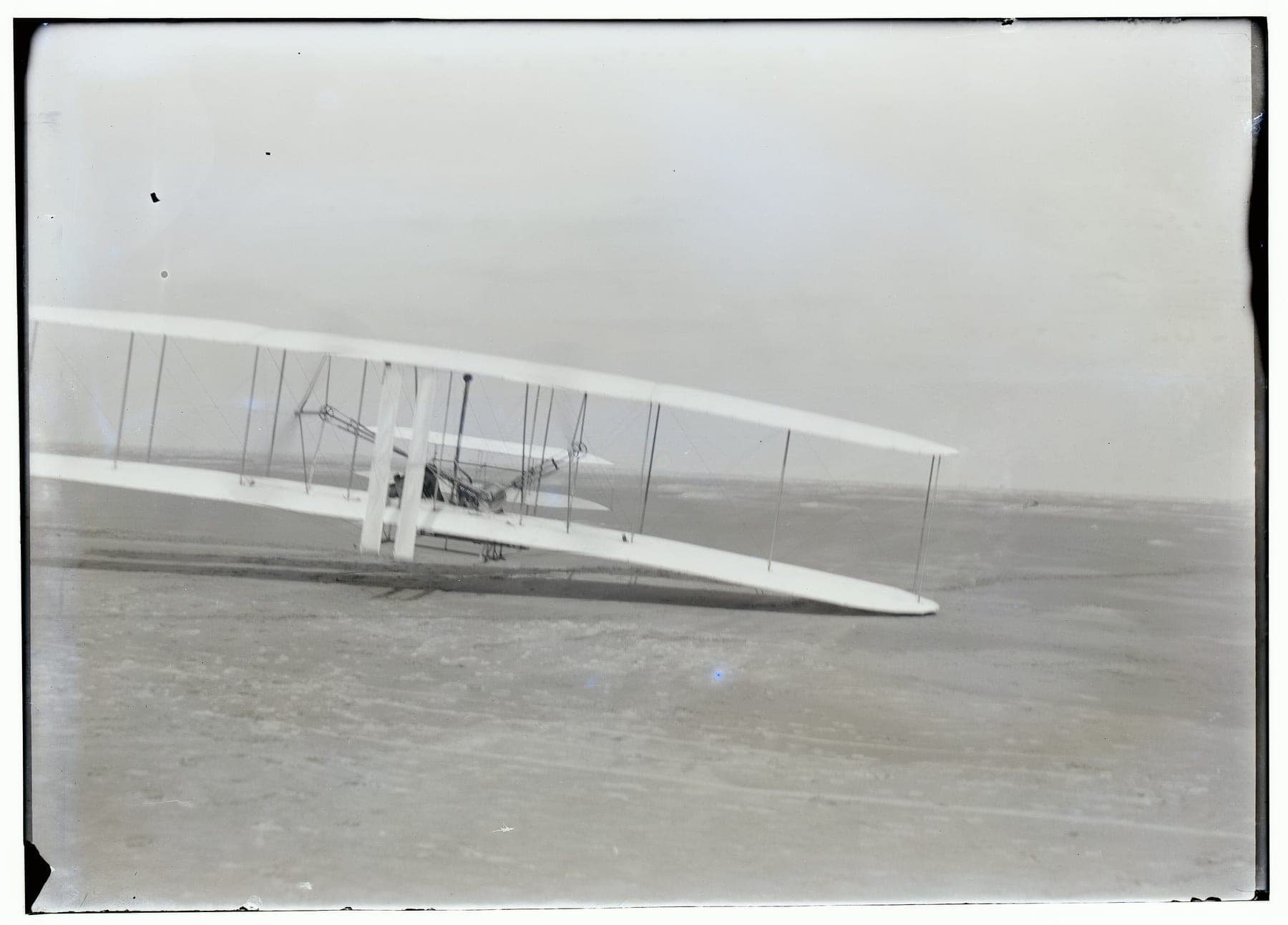 Orville Wright effectuant le troisième vol du 17 décembre 1903, la machine rasant le sable.