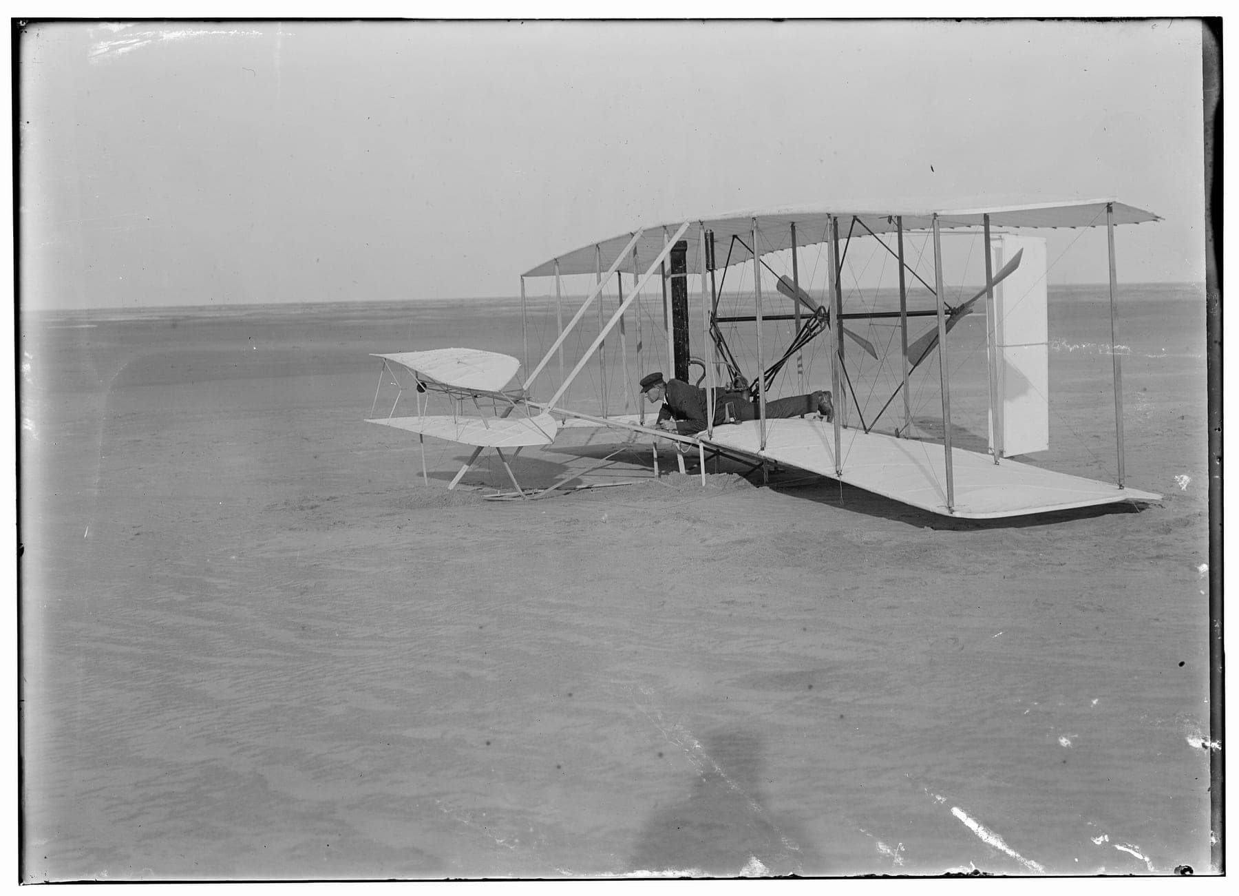 Wilbur Wright allongé aux commandes de la machine endommagée après l'essai manqué du 14 décembre 1903.