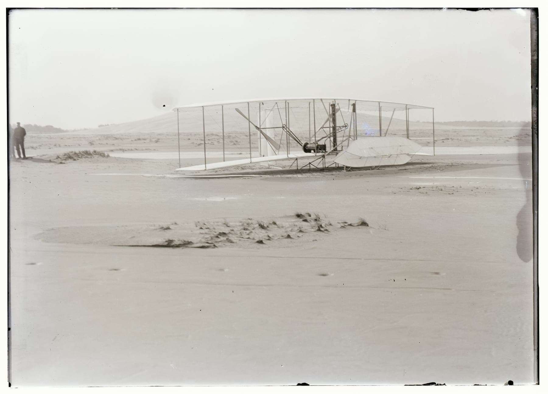 Le Flyer sur le sable après que la rafale l'eut retourné, le bâti de la gouverne brisé et les ailes froissées.