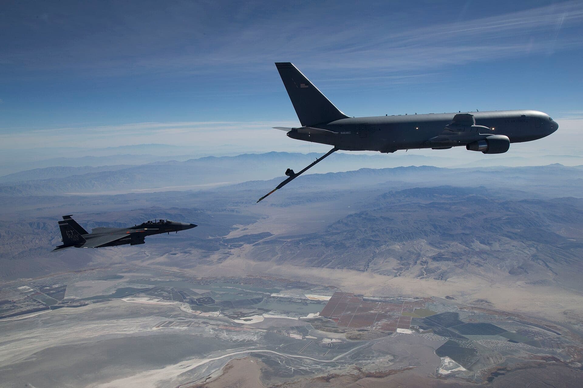 Un ravitailleur Boeing KC-46A Pegasus ravitaillant un F-15 en vol, sa perche déployée vers l'appareil receveur
