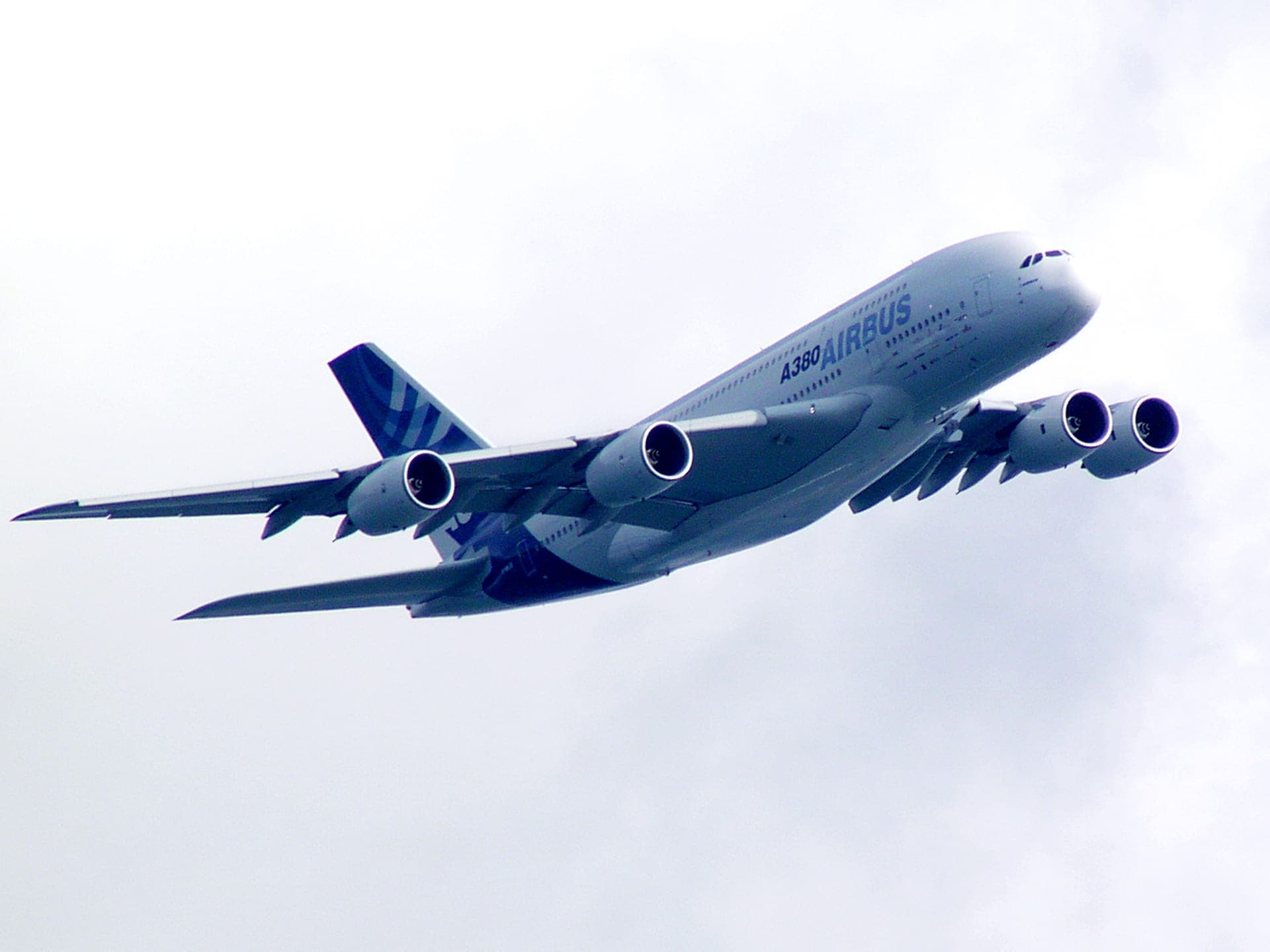 Un Airbus A380 volant à basse altitude au-dessus de Victoria Harbour, à Hong Kong, la skyline de la ville visible en dessous