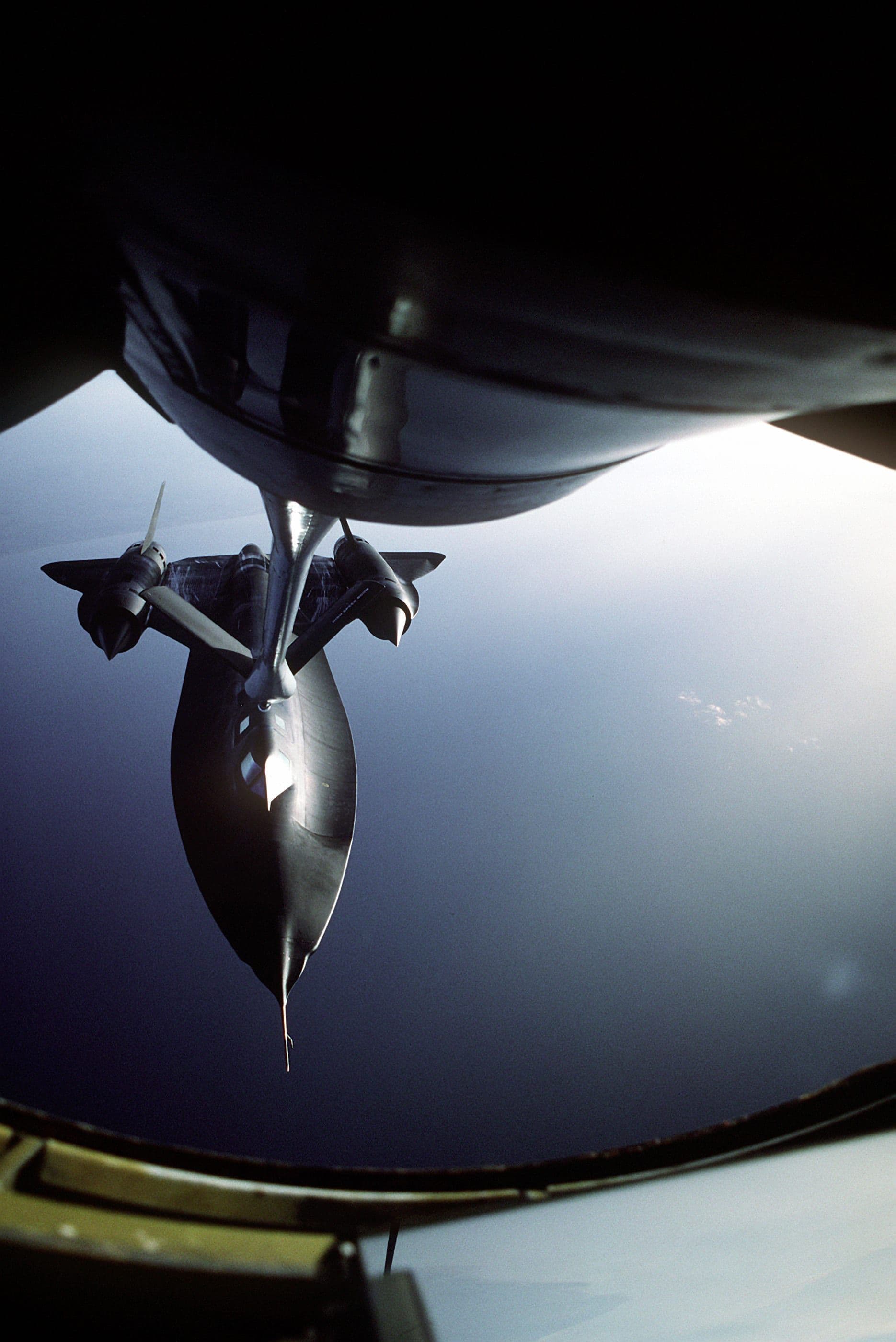 View from a tanker's boom operator station looking down at an SR-71 approaching to take on fuel