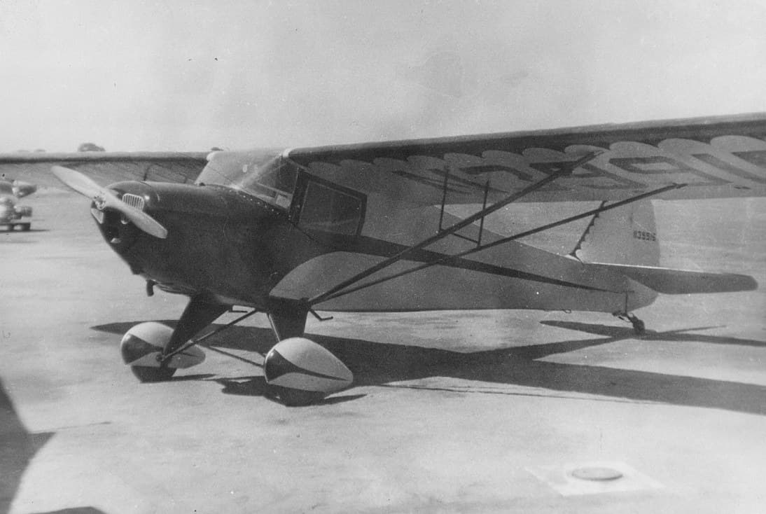 A yellow Taylorcraft BC-12D parked on an airfield apron