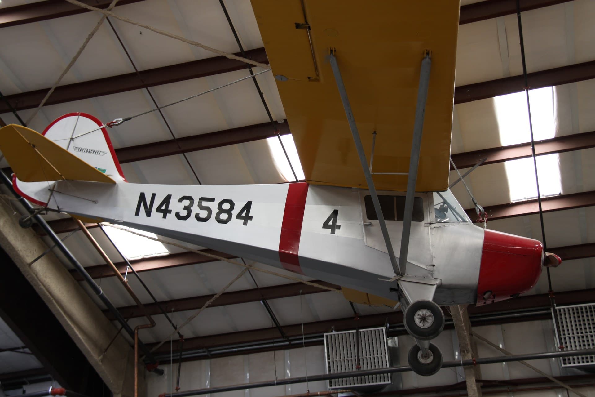 A restored Taylorcraft BC-12D with side-by-side seating parked on grass